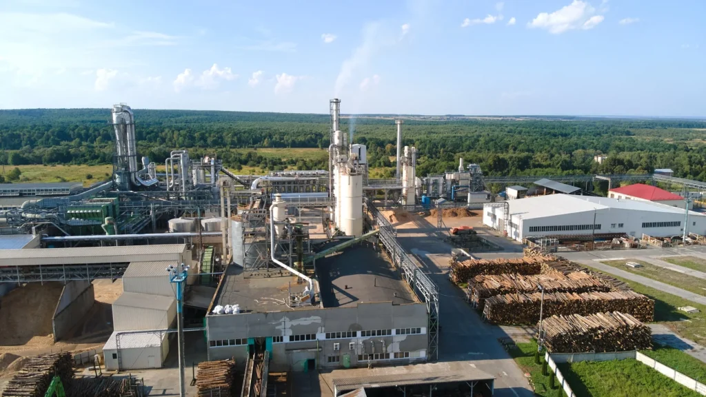 Industrial biomass processing facility with woody feedstock storage.
