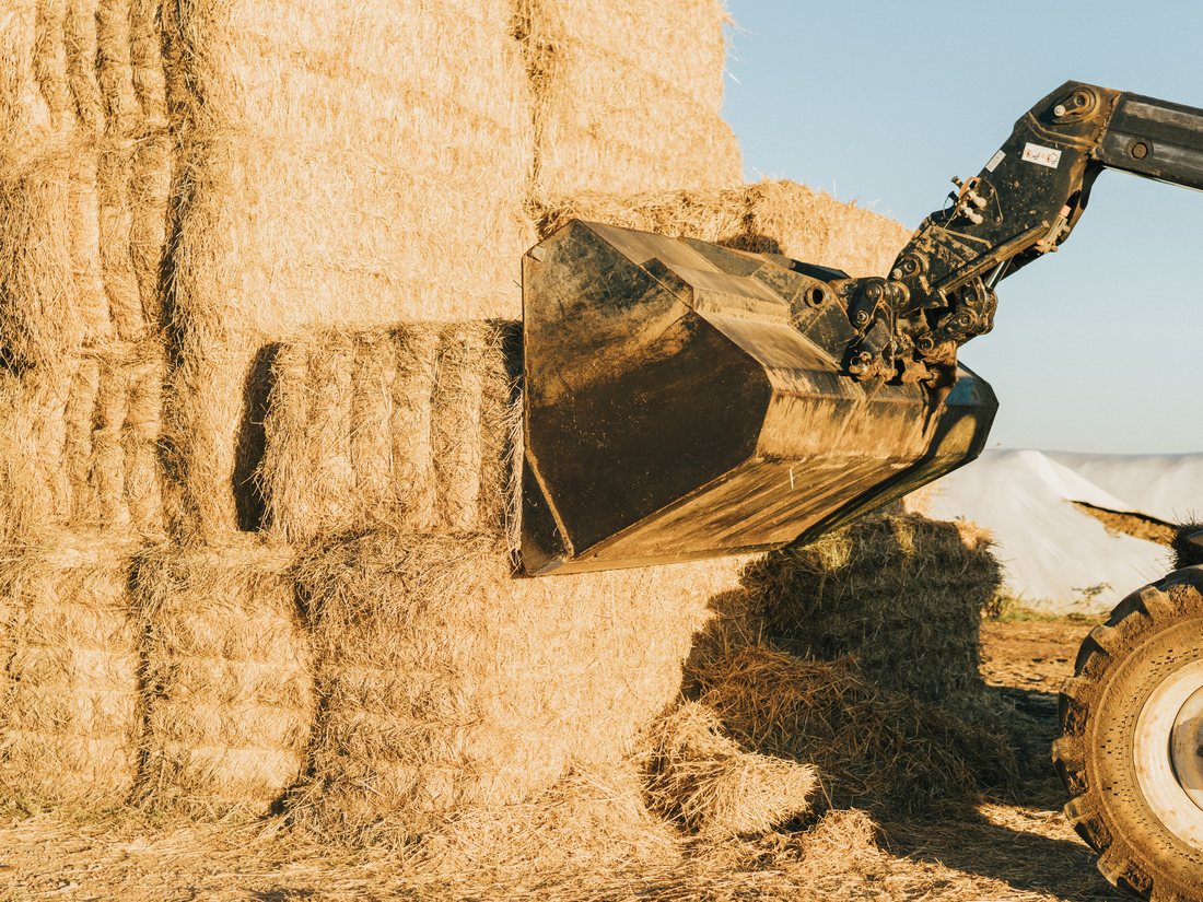 Loader collecting bales of agricultural biomass for supply chain handling