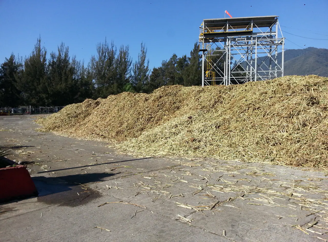 Large feedstock stockpile beside an industrial plant and storage infrastructure