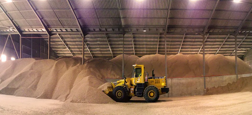 Large indoor biomass residue stockpile handled by industrial equipment